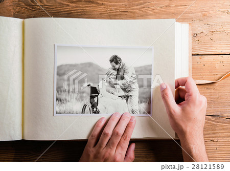 Hands holding photo album with picture of senior 28121589