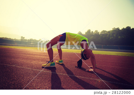 young asian woman backbending on stadium track 28122000