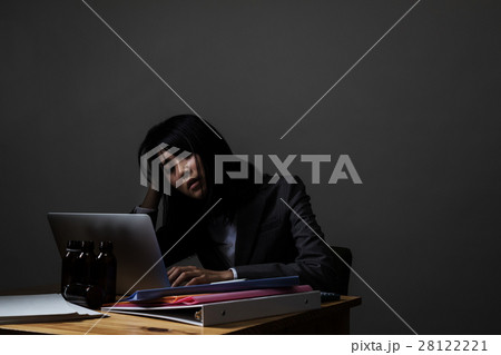 残業 こめかみを押さえるの写真素材