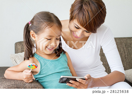 happy mother and daughter enjoying smartphone 28125638