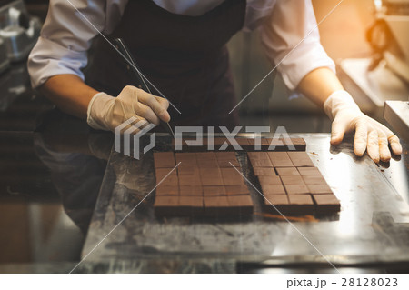 Chef cutting homemade chocolate in kitchen. 28128023