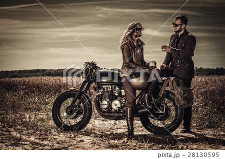 Young, stylish cafe racer couple on vintage custom 28130595