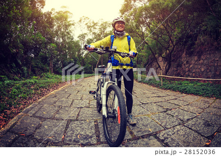 woman cyclist riding mountain bike on forest trail 28152036