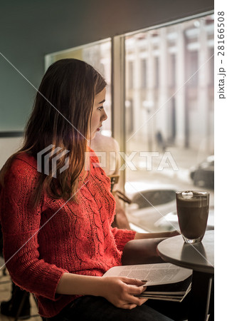 Young girl reading magazine in a cafe with cacao Young girl reading magazine in a cafe with cacao 28166508