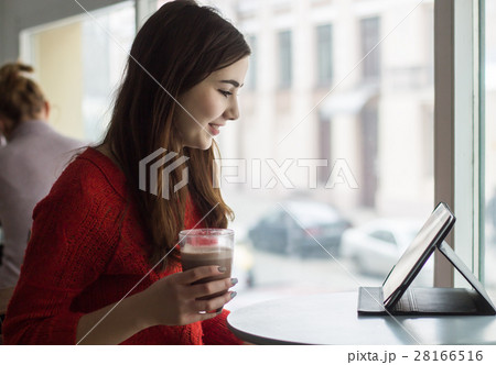 Young girl looking at tablet and smiling in cafe Young girl looking at tablet and smiling in cafe 28166516
