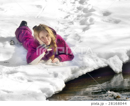 Happy girl lying on the snow in winter Happy girl lying on the snow in winter 28168044