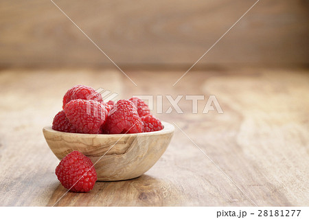 wood bowl full of ripe raspberries on old wooden table 28181277