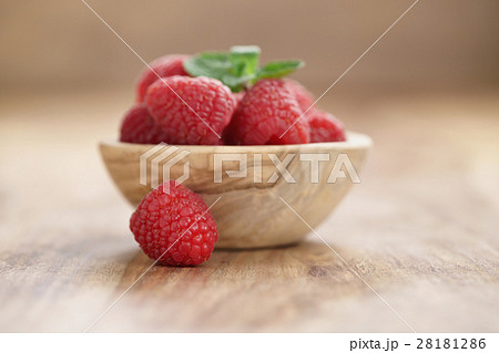 wood bowl full of ripe raspberries with mint leaves on old wooden table wood bowl full of ripe raspberries with mint leaves on old wooden table 28181286
