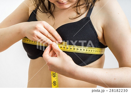 Woman is measuring her breast size with a tape. Woman is measuring her breast size with a tape. 28182230