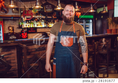 Bearded barman with tattoos and watches wearing an 28191677