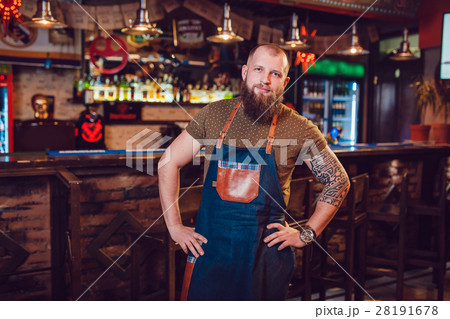 Bearded barman with tattoos and watches wearing an Bearded barman with tattoos and watches wearing an 28191678
