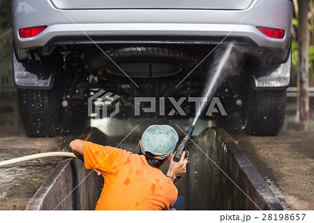Man spraying pressure washer for car wash in car care shop. Focus on car Man spraying pressure washer for car wash in car care shop. Focus on car 28198657