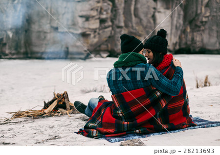 Couple sitting near a bonefire. They are covered Couple sitting near a bonefire. They are covered 28213693