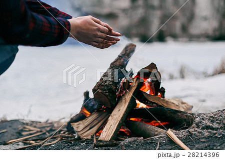 Girl warms hands near a fire in winter Girl warms hands near a fire in winter 28214396