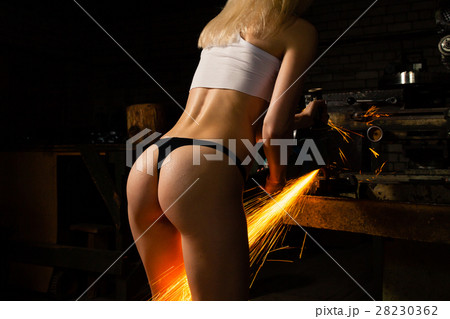 Young woman working with the grinder in the garage Young woman working with the grinder in the garage 28230362