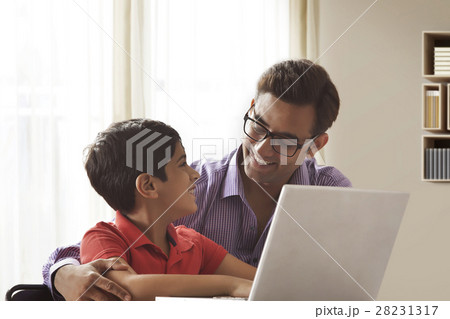 Father and son using a laptop and smiling 28231317