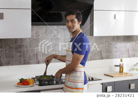 Young man cooking food in kitchen 28231421