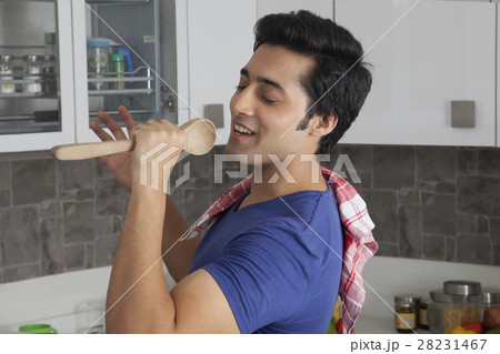 Young man singing into wooden spoon 28231467