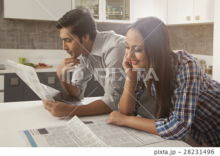 Young couple reading newspaper at kitchen table 28231496