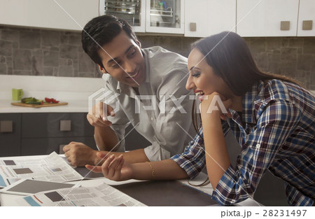 Young couple reading newspaper at kitchen table 28231497
