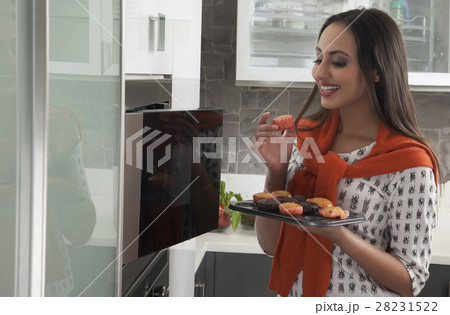 Young woman baking cupcakes in oven 28231522