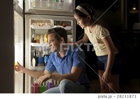 Father and daughter keeping food in refrigerator at night 28231871