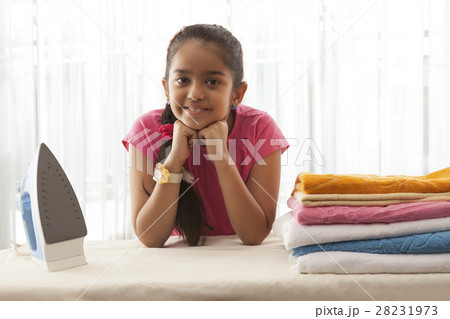 Smiling girl leaning on ironing board with hands on chin 28231973