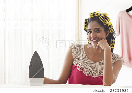 Young woman with hair curlers holding iron appliance Young woman with hair curlers holding iron appliance 28231982