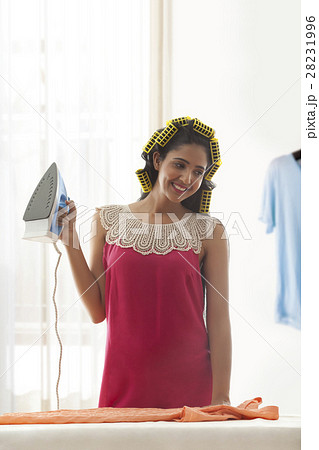 Young woman in hair curlers holding iron Young woman in hair curlers holding iron 28231996