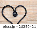 Medical stethoscope in a heart shape on wood table 28250421