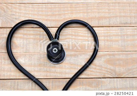 Medical stethoscope in a heart shape on wood table 28250421