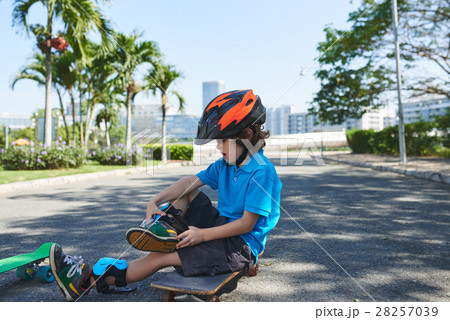 Little boy putting on knee pads Little boy putting on knee pads 28257039