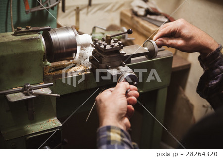 Man makes wood detail on lathe 28264320