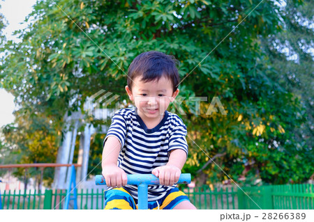 Asian kid riding seesaw board at the playground Asian kid riding seesaw board at the playground 28266389