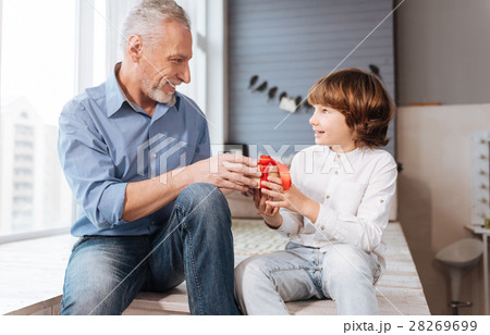 Cheerful elderly man giving a present to his Cheerful elderly man giving a present to his 28269699