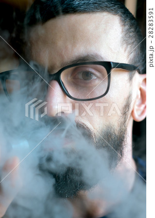 Bearded man smoking vaporizer and blows smoke 28283591