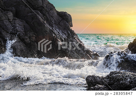 Sea waves and splashes breaking on rocks in sunset 28305847