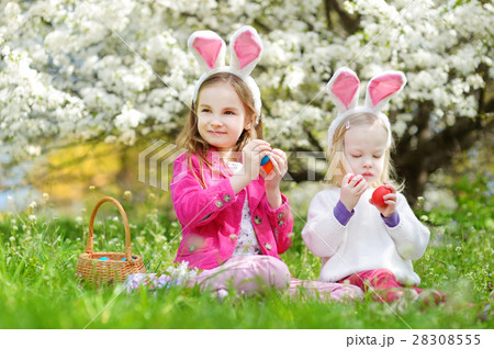 Two adorable little sisters playing with Easter eggs on Easter day Two adorable little sisters playing with Easter eggs on Easter day 28308555