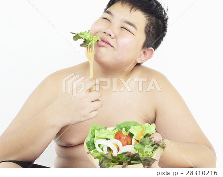 A fat boy is happily eating vegetable salad A fat boy is happily eating vegetable salad 28310216
