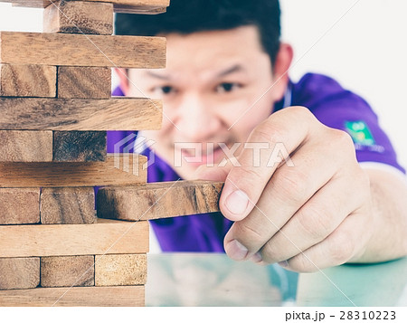 Asian guy is playing a wood blocks tower game Asian guy is playing a wood blocks tower game 28310223