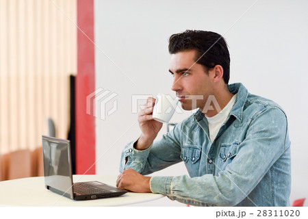 Good looking man wearing denim shirt sitting in a coffee bar Good looking man wearing denim shirt sitting in a coffee bar 28311020