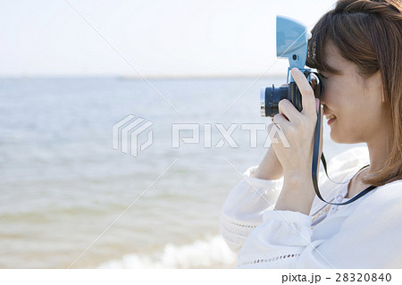 海辺でカメラを構える女性の写真素材 2840