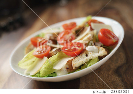 fresh caesar salad with chicken and cherry tomatoes on wood table 28332032