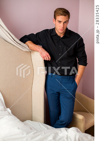 Young man standing in bedroom. 28335425