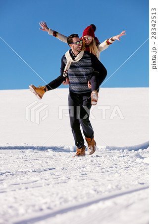 Couple playing in snow. Man giving woman piggyback 28342513