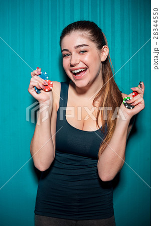 Young girl holding poker chips on blue background Young girl holding poker chips on blue background 28344550