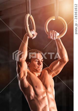 Young muscular man doing exercises with rings 28361612