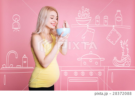 Positive pregnant woman eating in the kiitchen Positive pregnant woman eating in the kiitchen 28372088