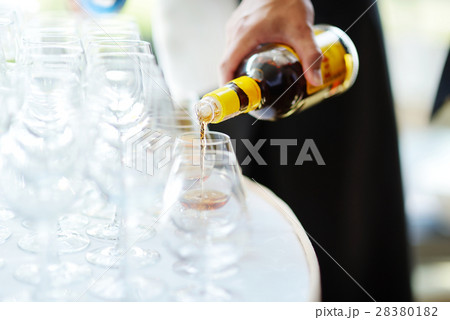 Pouring alcohol into a glasses on a festive event Pouring alcohol into a glasses on a festive event 28380182
