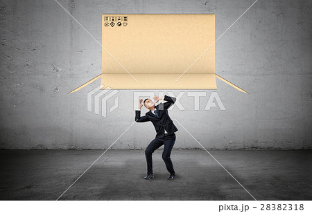 Businessman on concrete background cowering below 28382318